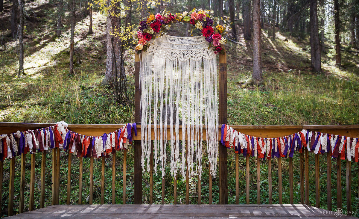 Pretty outdoor mountain wedding with custom Macrame backdrop at Beaver Meadows in Conifer CO
