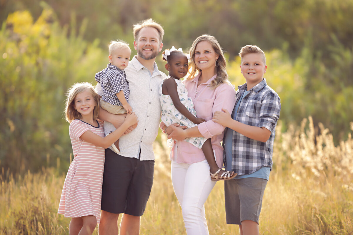 Family-Photos-yvonne-min-photography-parents-sister-brother-holding-kids-outside-field-golden-hour-sunset-connection-child-thornton-adoption-kids-broomfield-north-denver-erie-westminster-canon-session-images-love-arvada-boulder-grass-sunlight-siblings