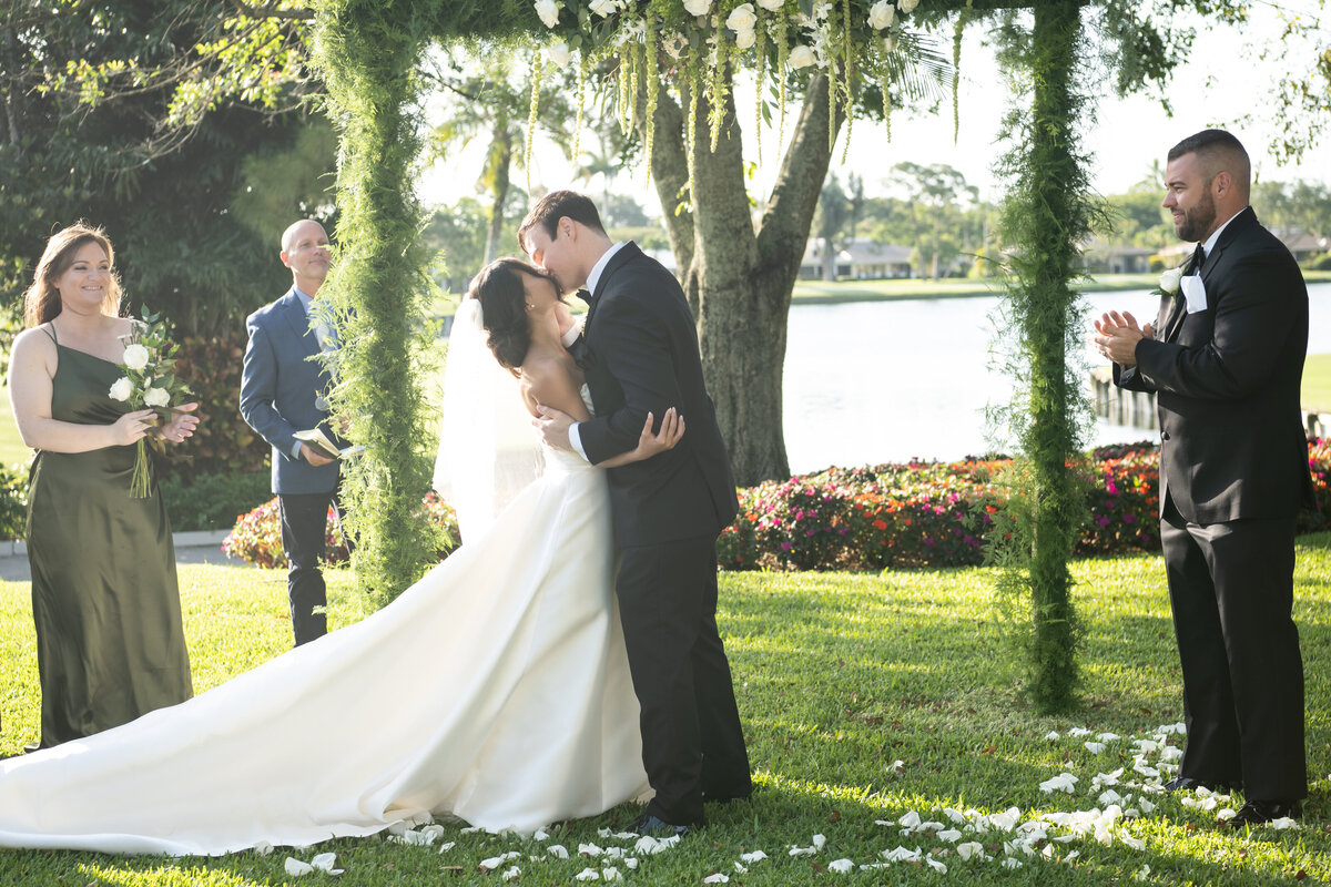 Bride and groom kissing under flower arch in Naples Florida