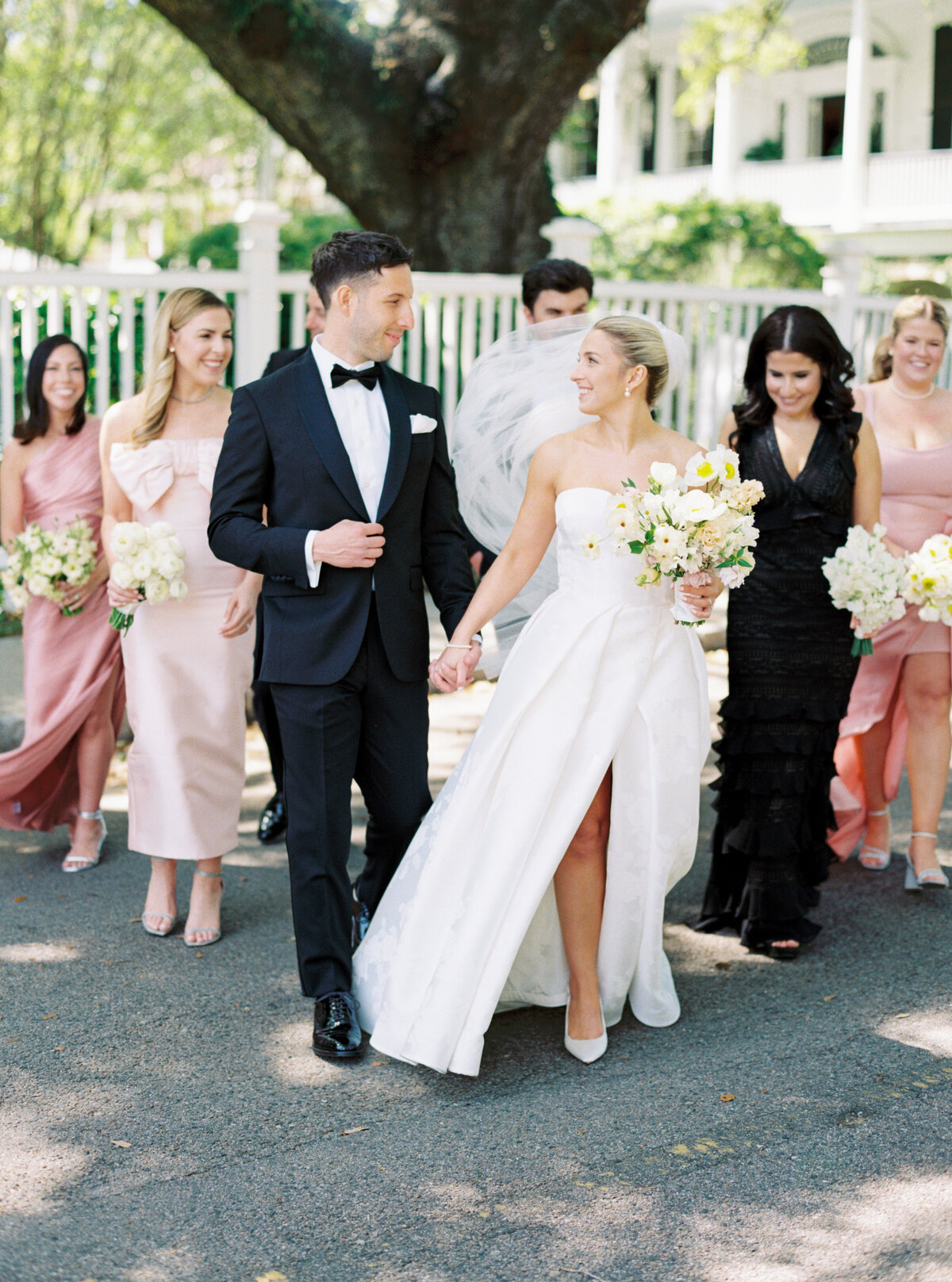 Bride and groom walking with the bridal party. Bridesmaids in pink dresses.