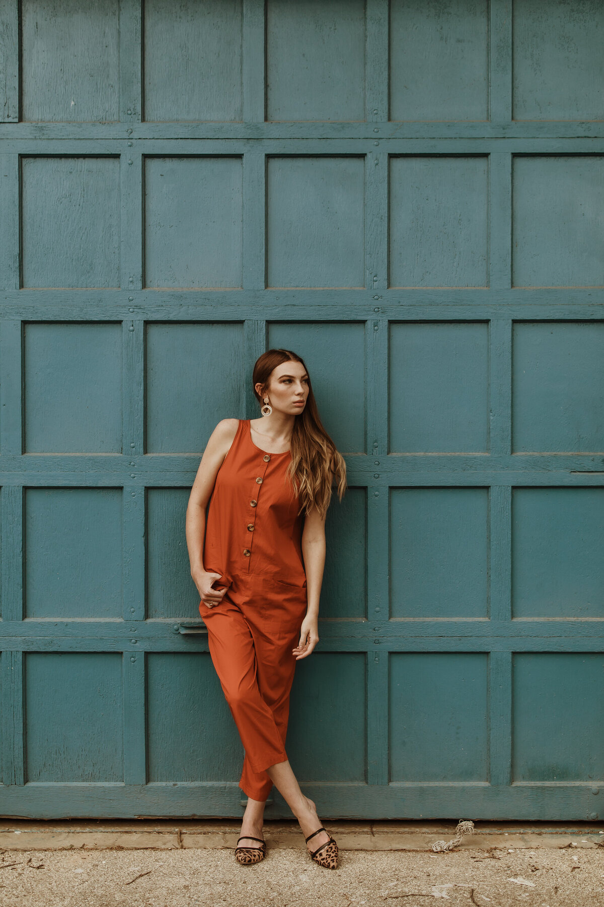 San Francisco Senior photography session of woman in orange jumpsuit in front of teal wall