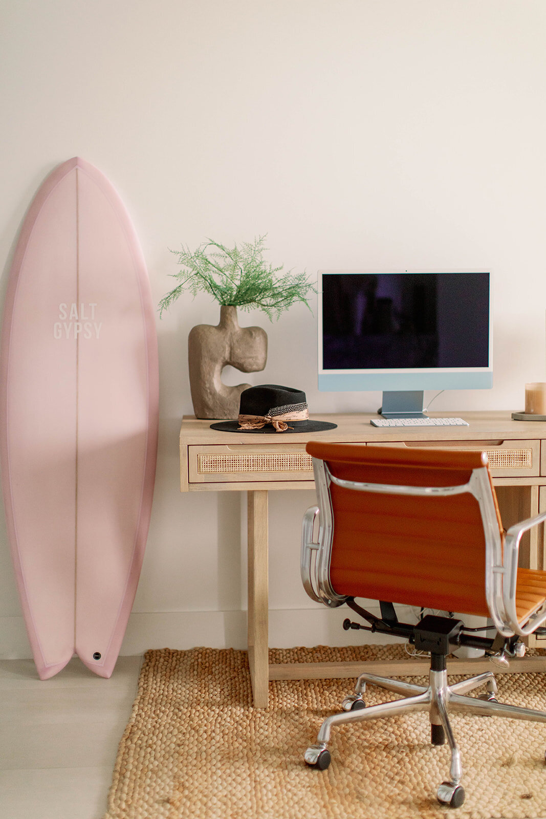 Wooden desk with leather chair and pink surf board