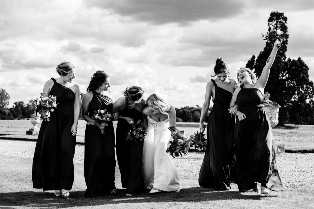 Brid with her bridesmaids at Gosfield Hall walking hand in hand