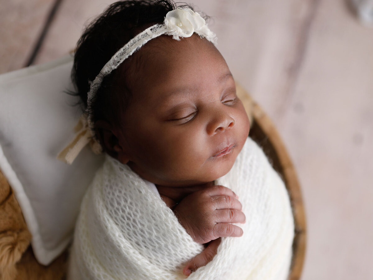 Newborn-photography-session-newborn-in-basket-wrapped-in-white-with-flower-headband,-photo-taken-by-Janina-Botha-photographer-in-Oakville-Ontario
