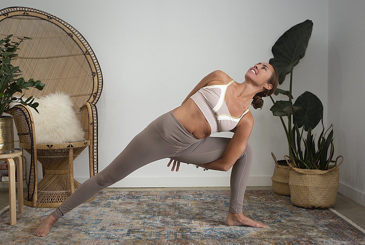 Female yogi holds bound crescent lunge twist yoga pose & smiles during yoga class at Hotsource Yoga in Aptos