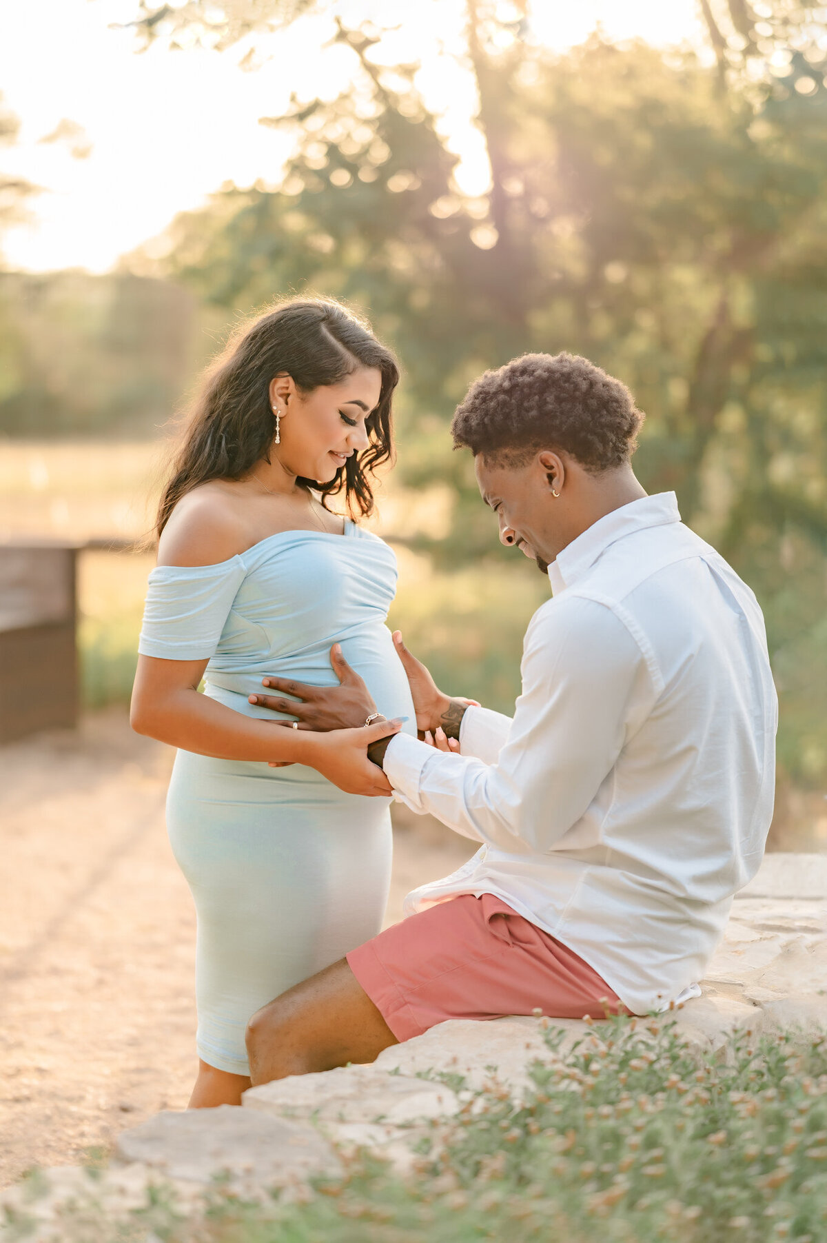 Expecting couple with hands on mama's belly in beautiful glowing light during maternity pictures.