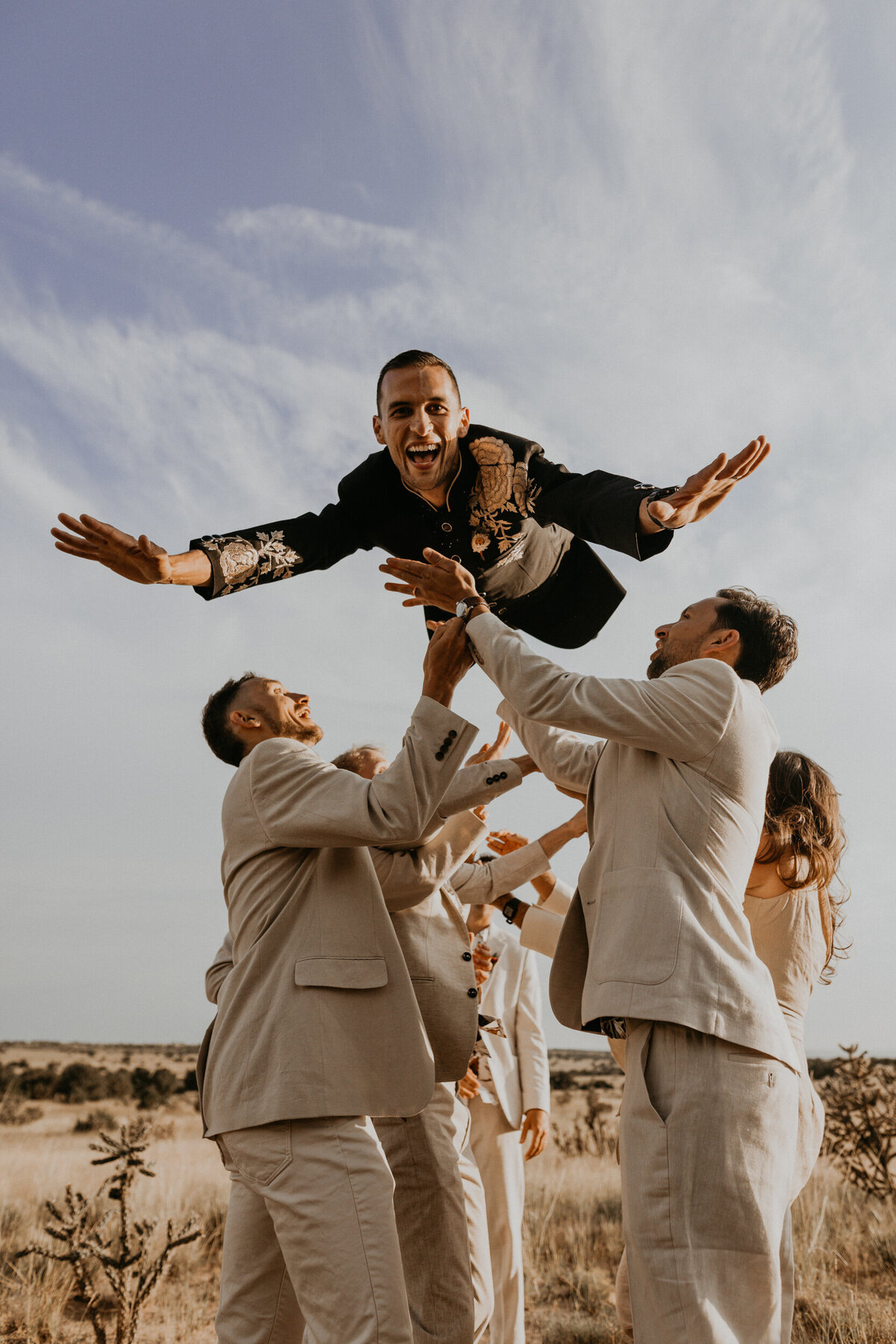 wedding party throwing groom into the air