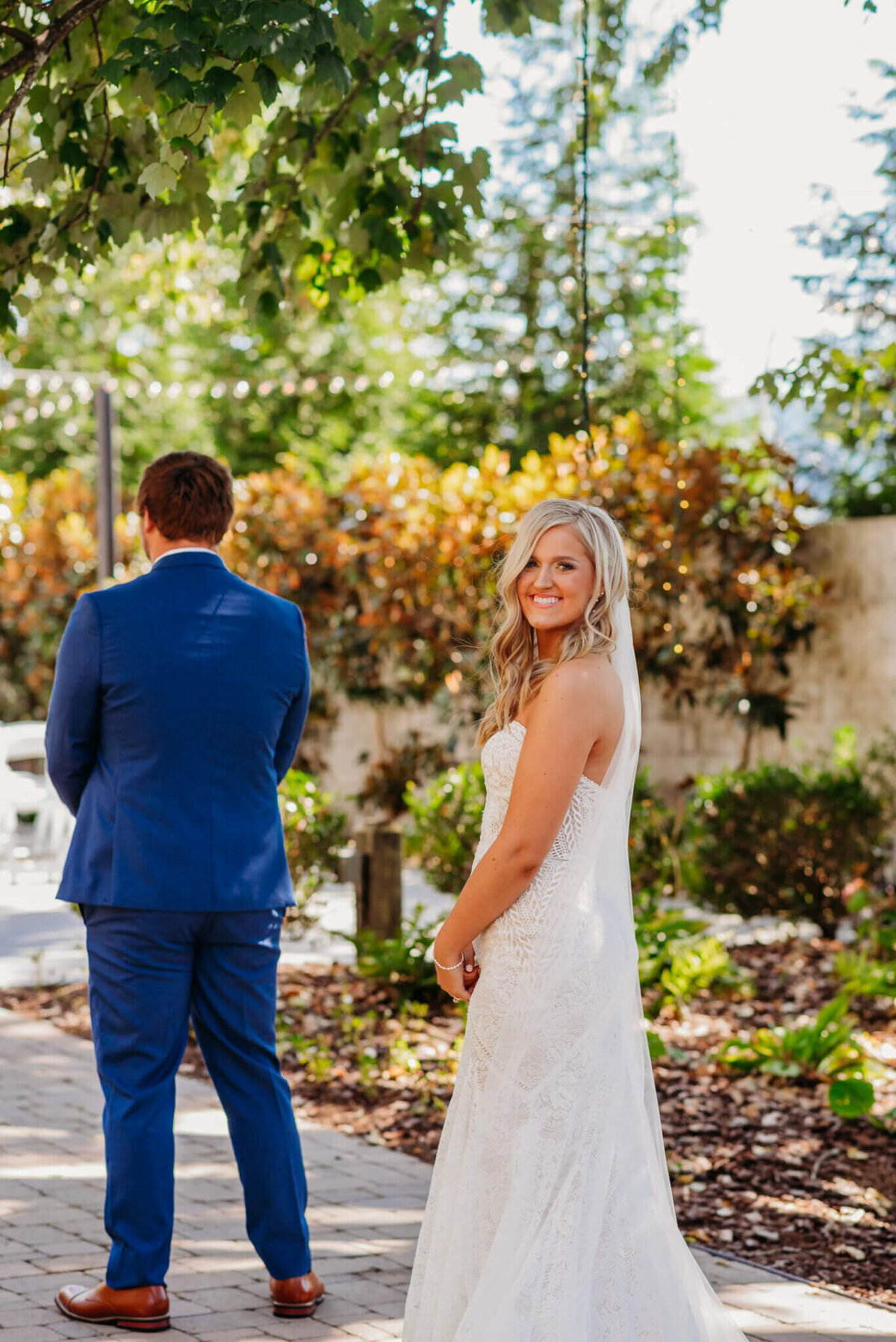 photo of a bride smiling over her shoulder while her groom faces away
