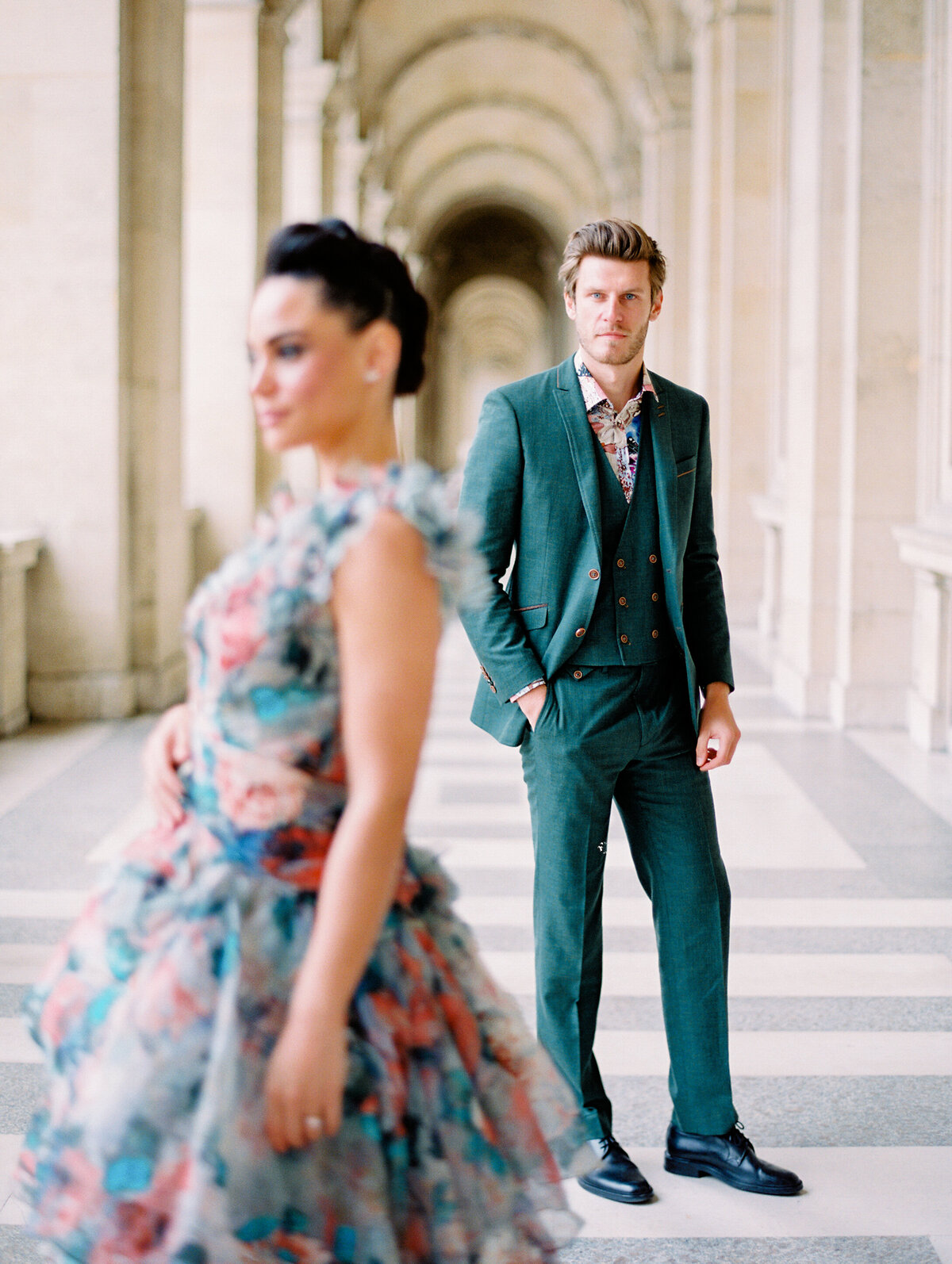 Film photograph of bride and groom at their elopement in Paris the bride is in a 3d print colorful pink and teal gown and the groom is in a forest green linen suit photographed by Italy wedding photographer