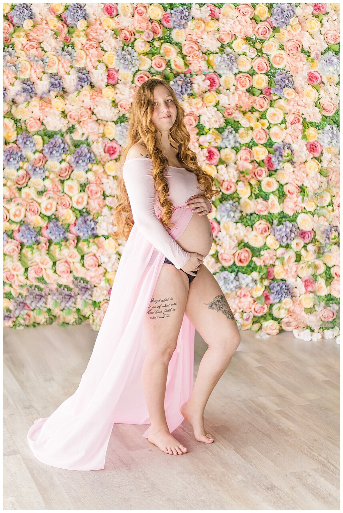 Maternity Photography in Wexford in studio where mom is in front of a lot of flowers in her pretty pink dress