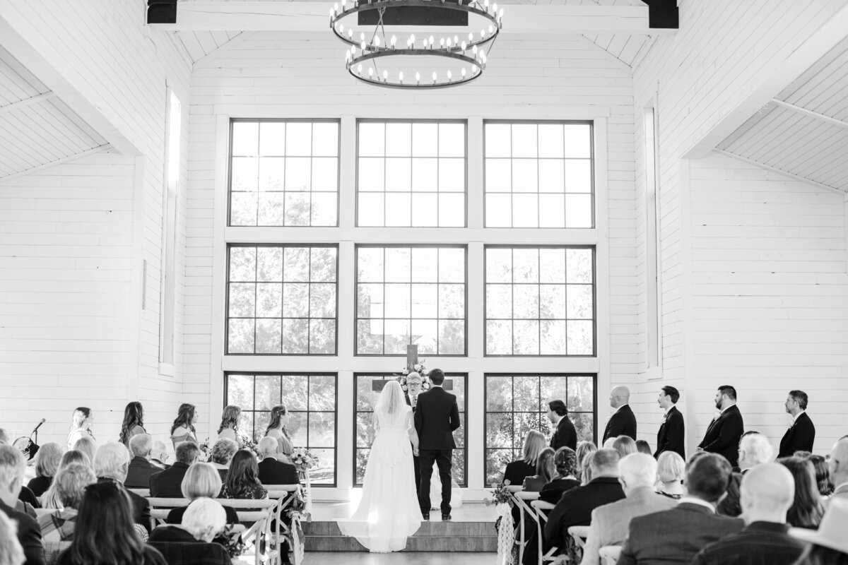 black and white image of bride and groom facing nine large windows Morgan Creek Barn in Dripping Springs
