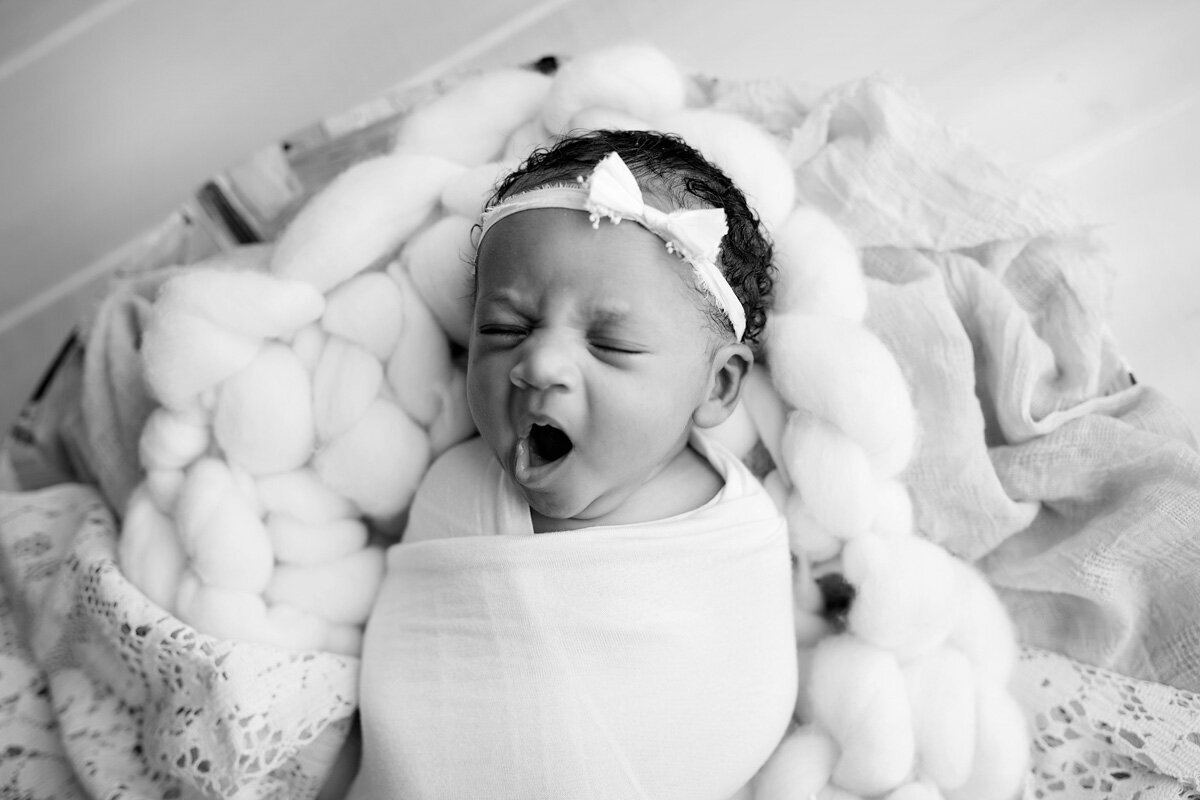 Newborn session with yawning baby girl wearing a bow