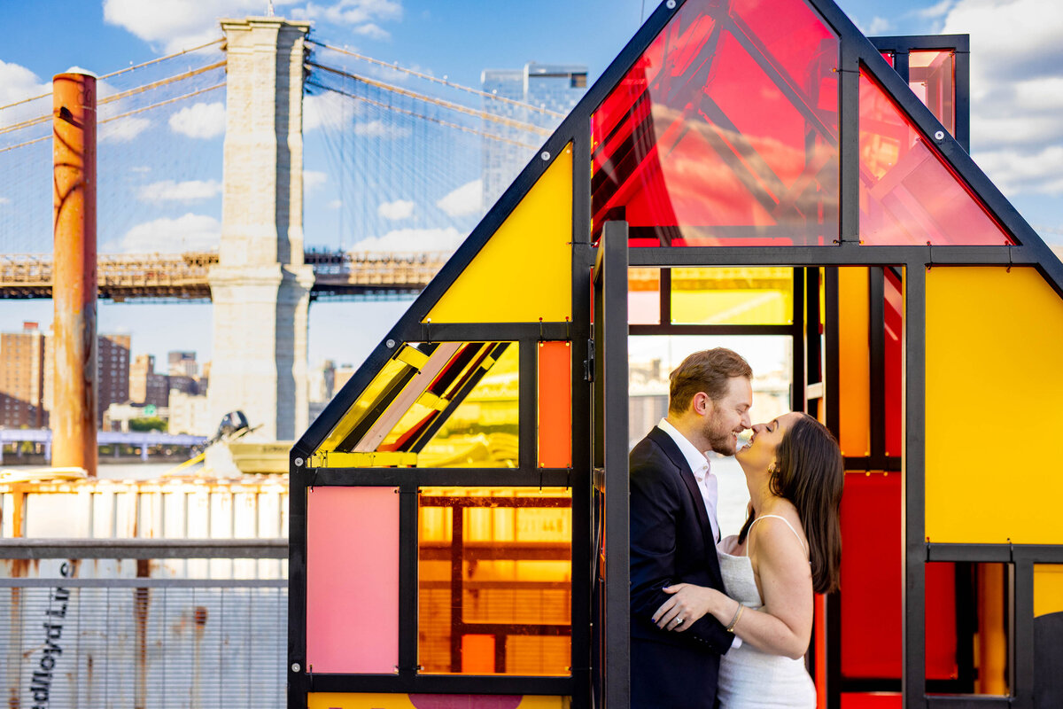 A couple kissing in a small glass structure.
