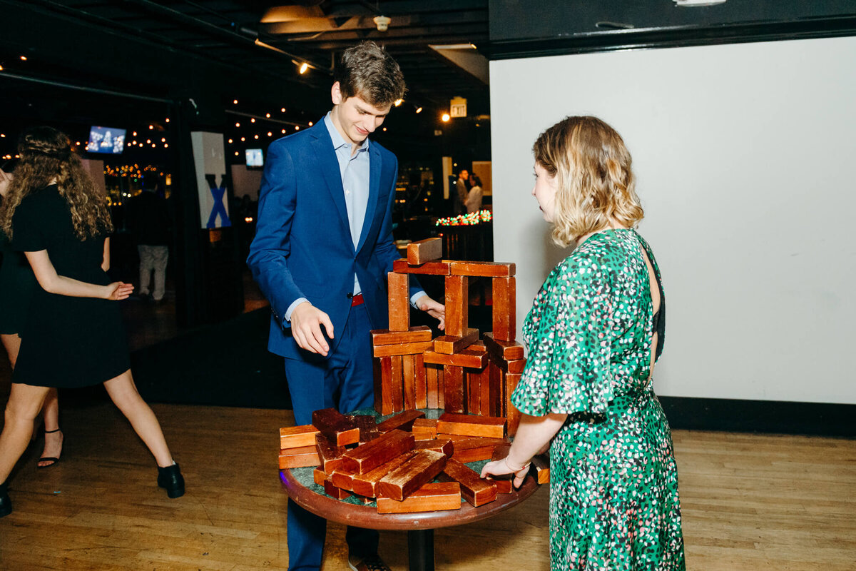 A teen boy and girl play with large wood blocks on a table
