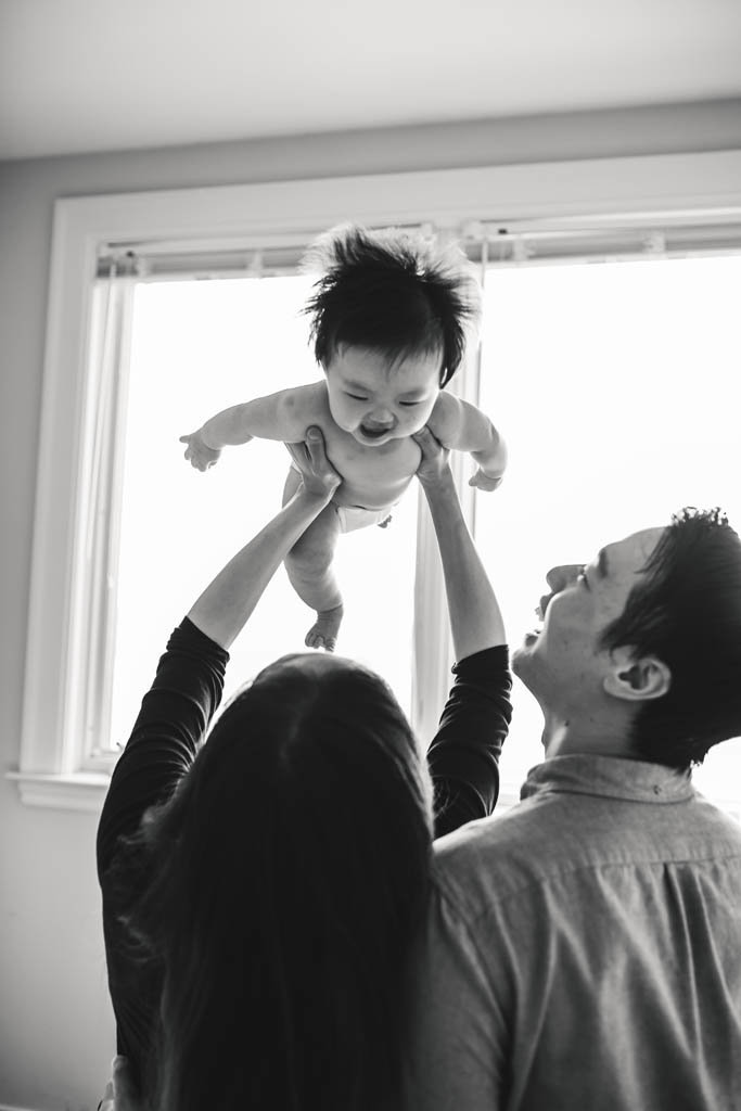 Bay Area mom holds baby in air at in home family photography session
