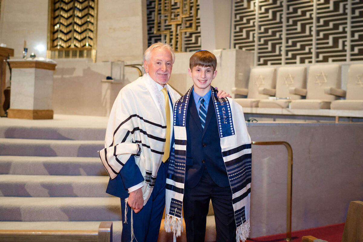 A grandfather stands at the steps to the bimah with his grandson for his Bellevue Bar and Bat Mitzvah Photography