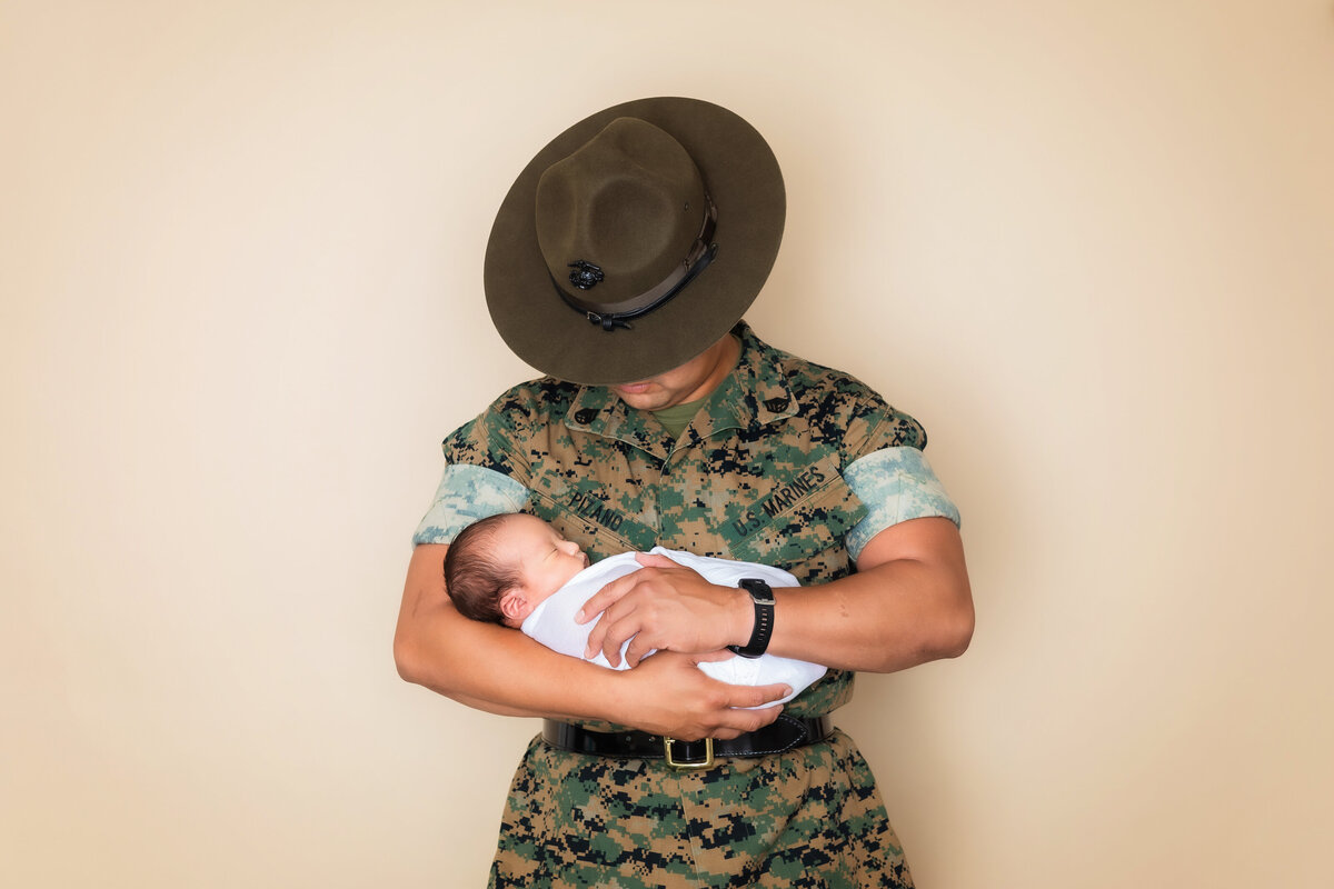 Newborn Photographer, a marine in camouflage holds his baby