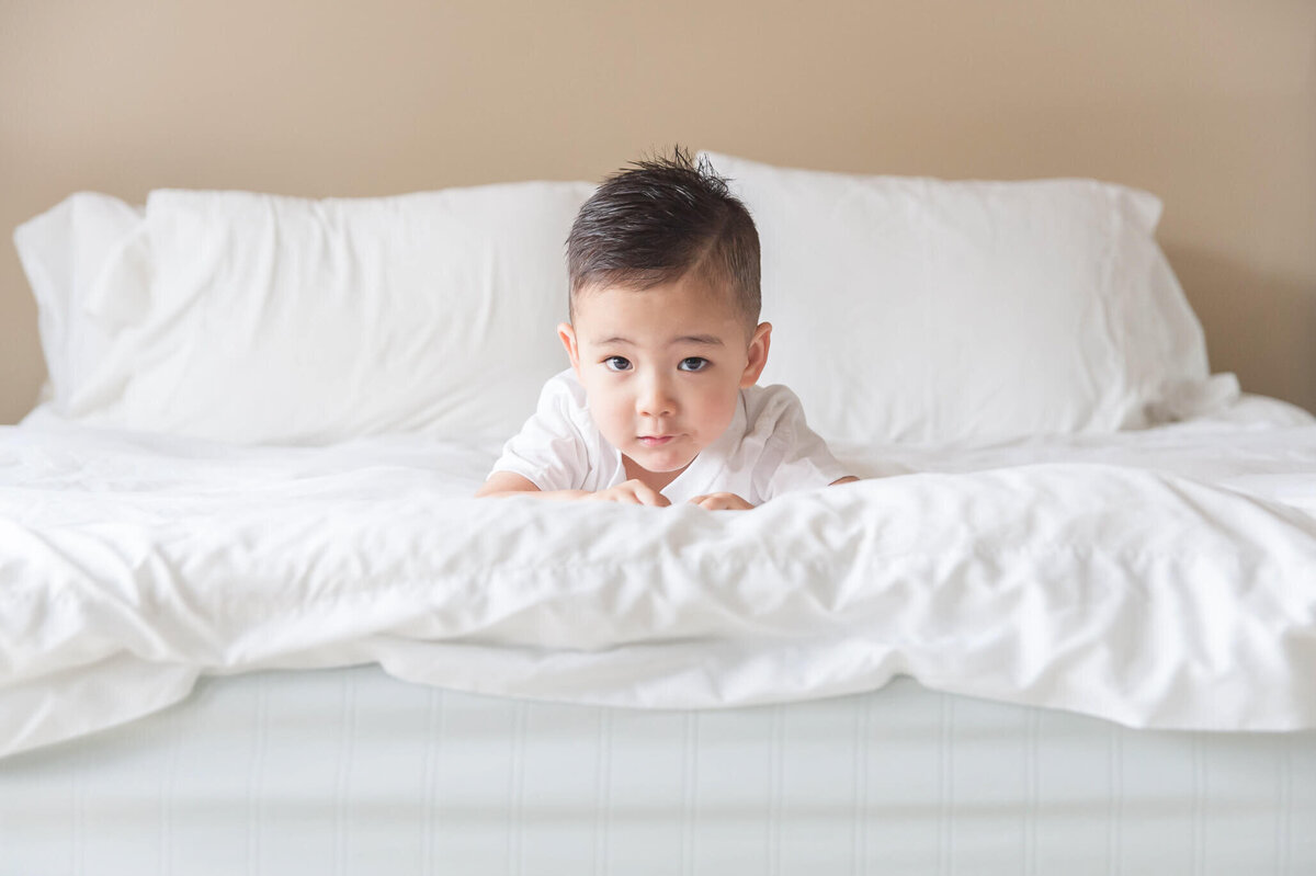 little boy at end of master bed looking at camera
