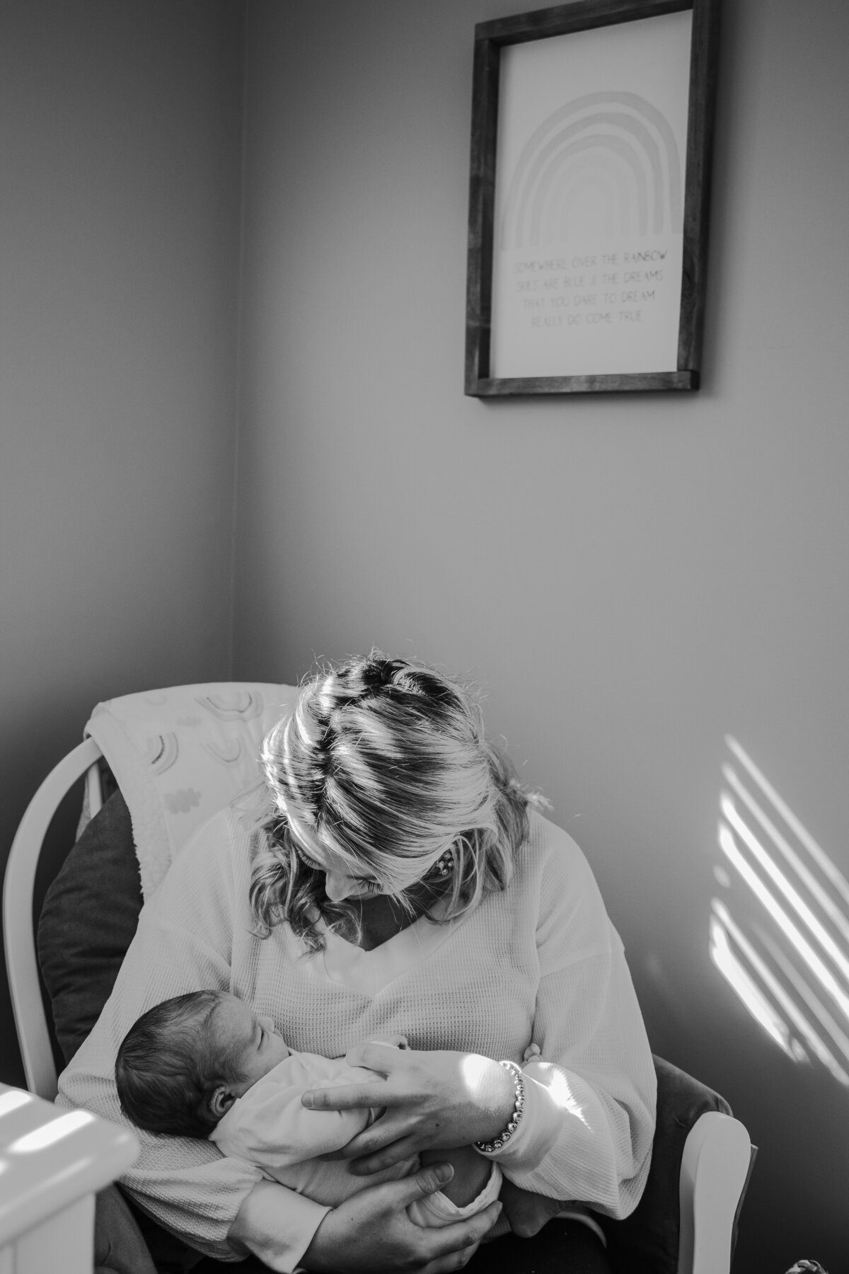 Newborn Photographer, a mother sits and breastfeeds her child