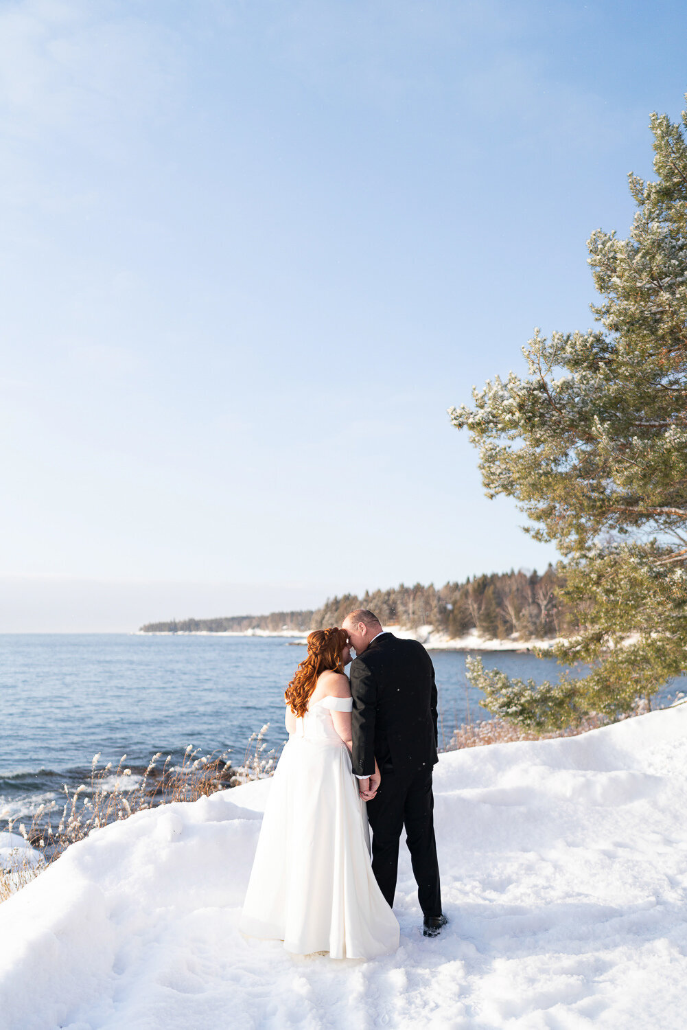 Bride and groom kiss in the snow in Two Harbors, Minnesota.