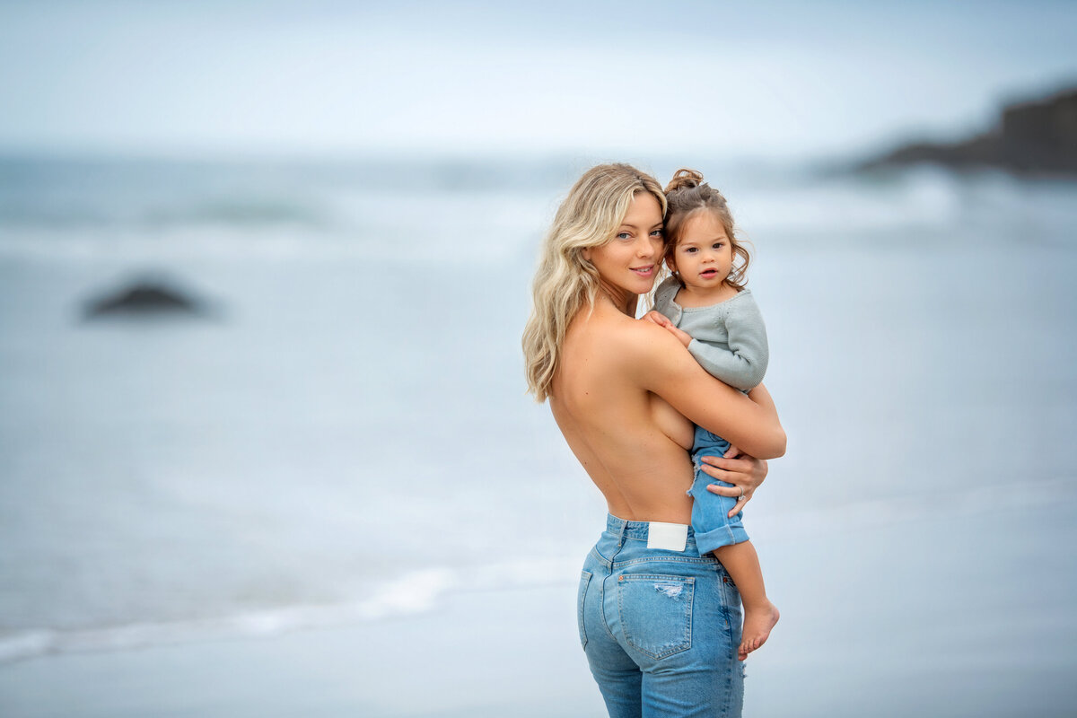 Topless mother and daughter in Malibu beach California taking pictures in the rain.