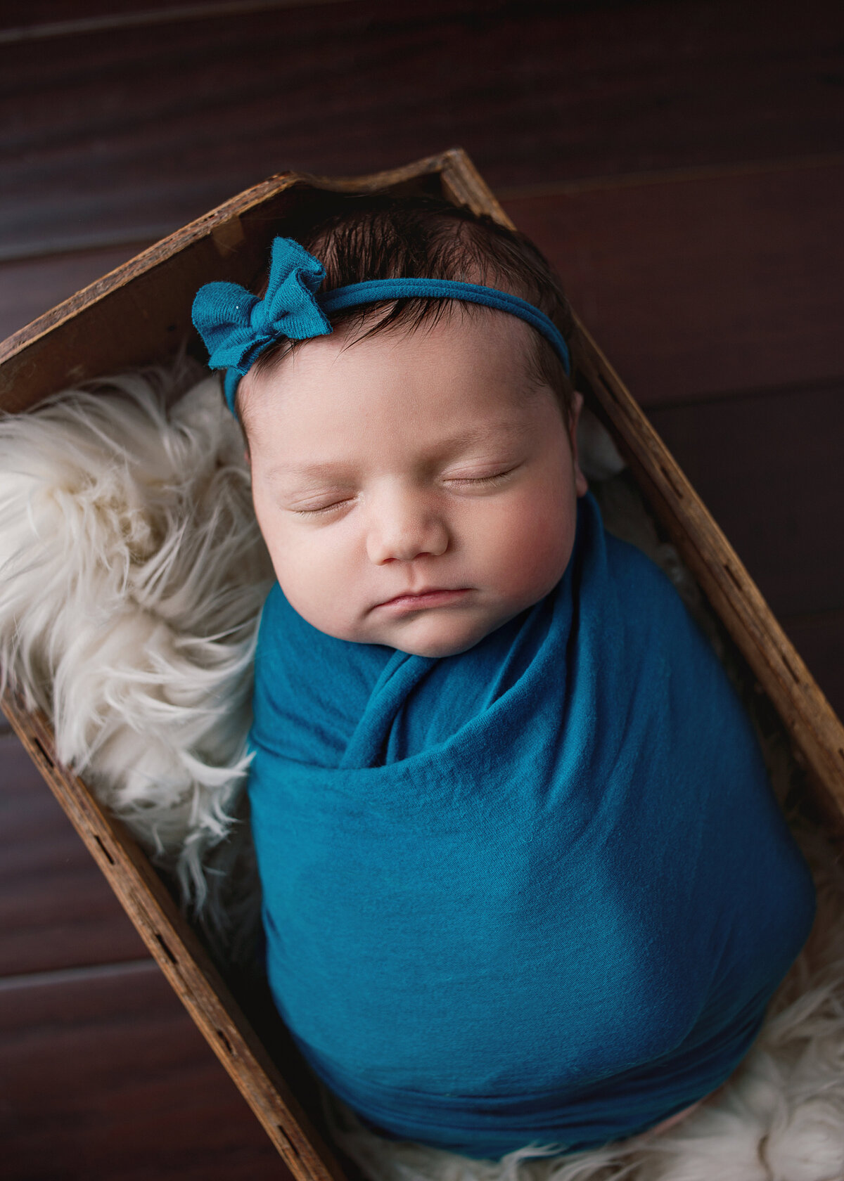 Newborn baby girl, wrapped in blue wrap wearing blue headband sleeping in box during newborn session in  Mount Juliet tennessee photography studio