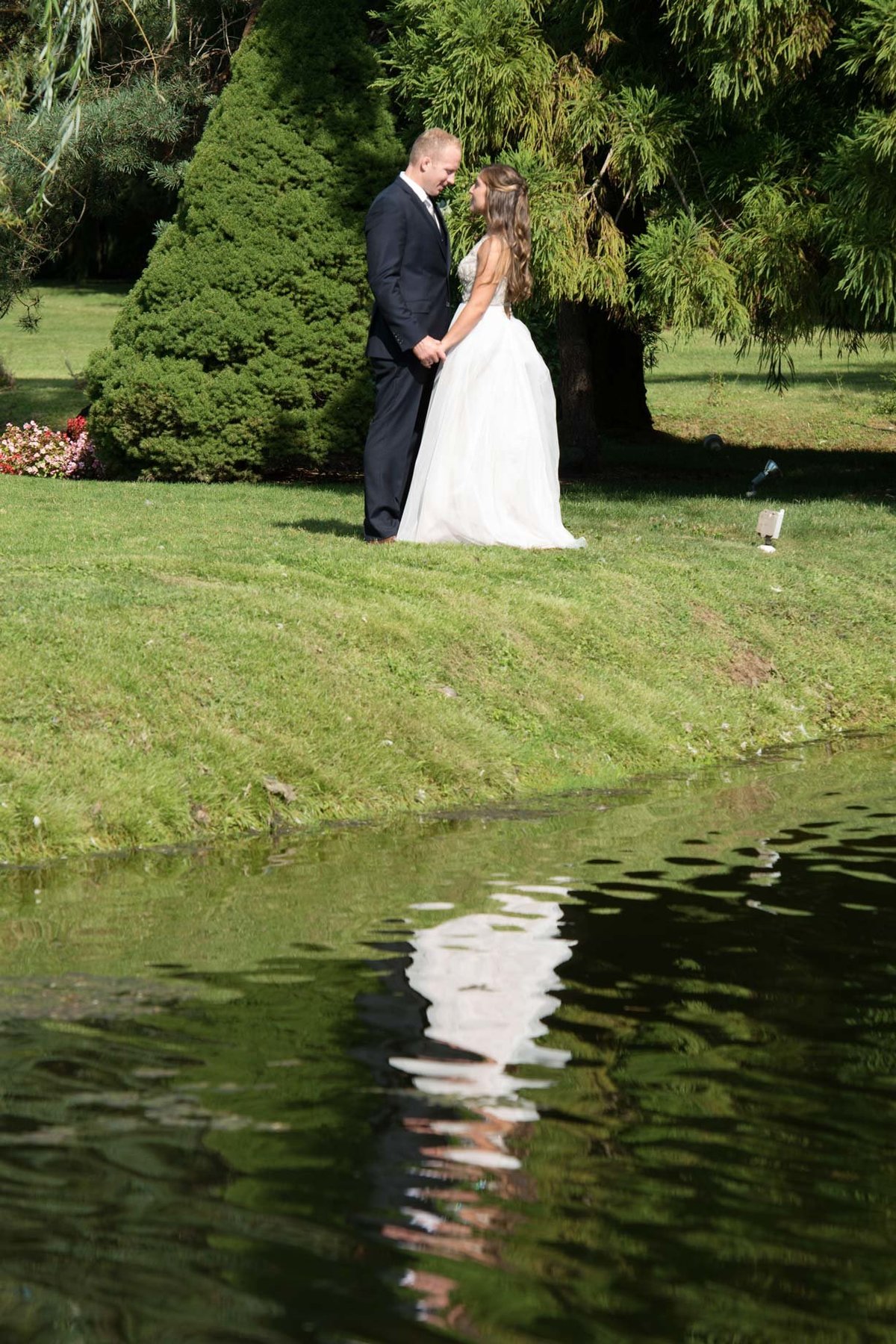 Bride and groom looking at one another right by the water at Flowerfield