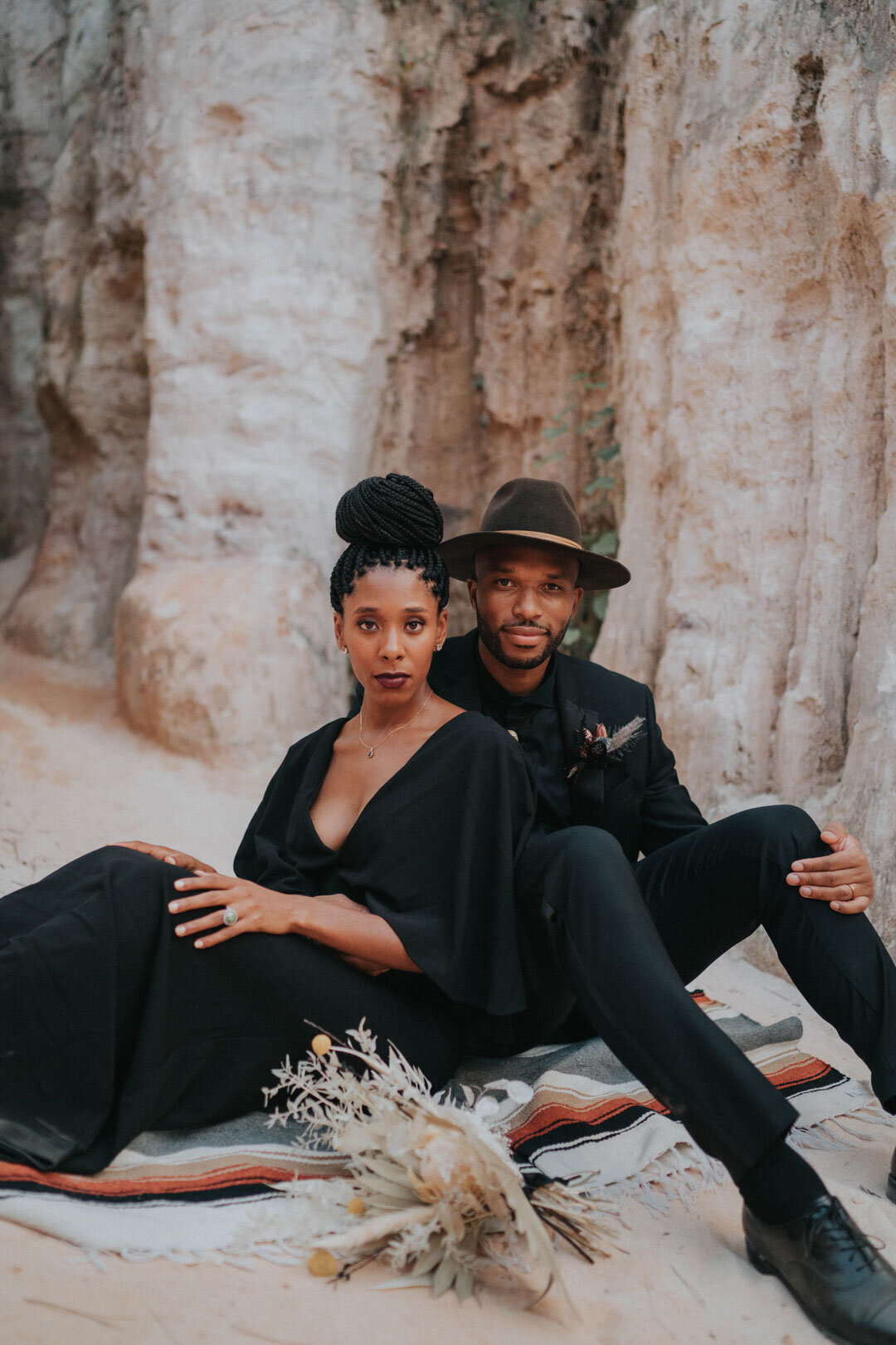 Black couple wearing black outfits sitting in the desert
