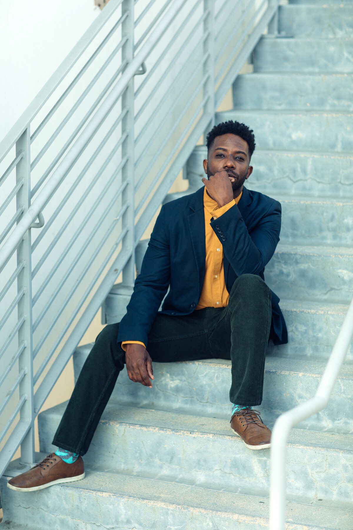 Portrait Photo Of Young Black Man Sitting On Stairs With One Hand On His Chin Los Angeles