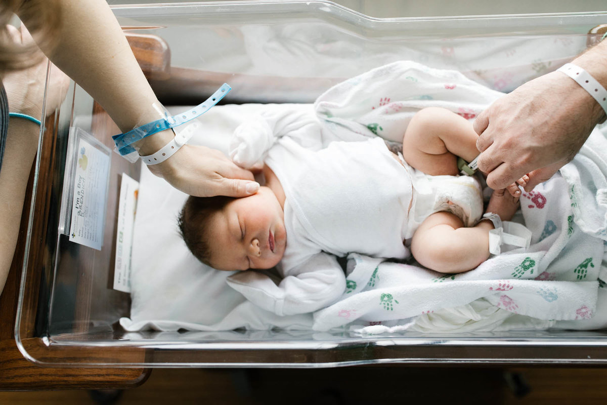 Laurie Baker photographs new parents touching their newborn for the first time in hospital
