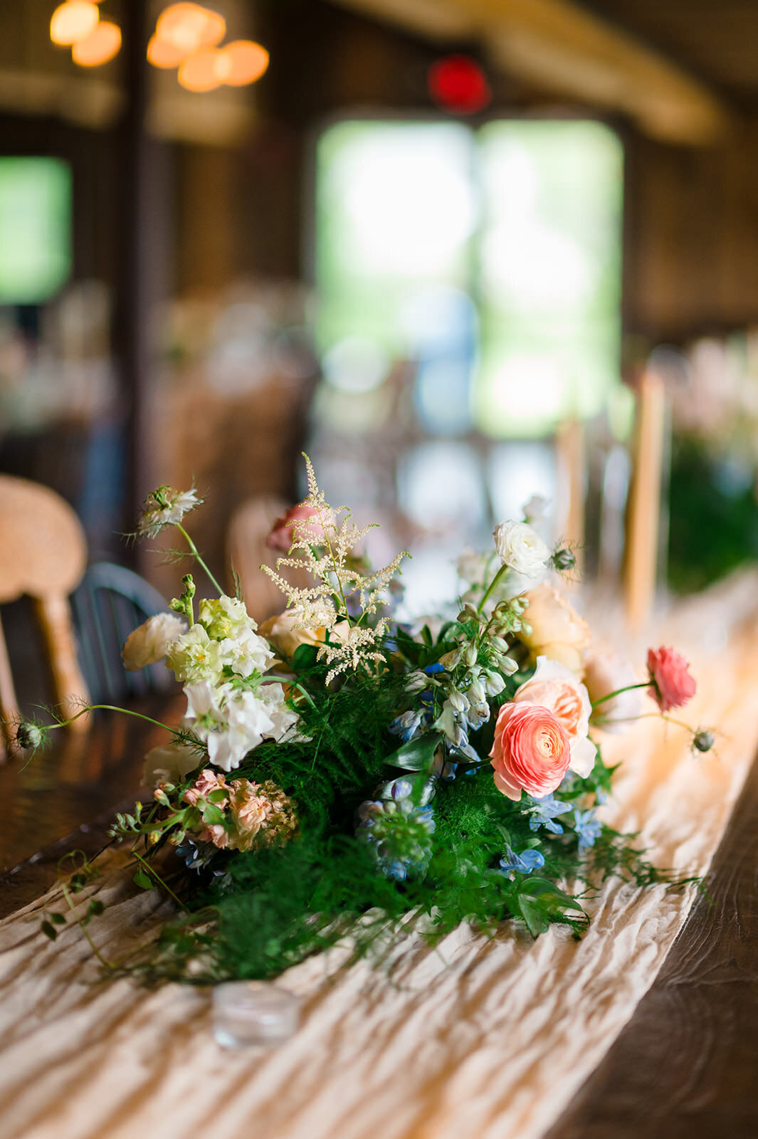 An elegant floral centerpiece with mixed blooms on a wooden table in a rustic setting.