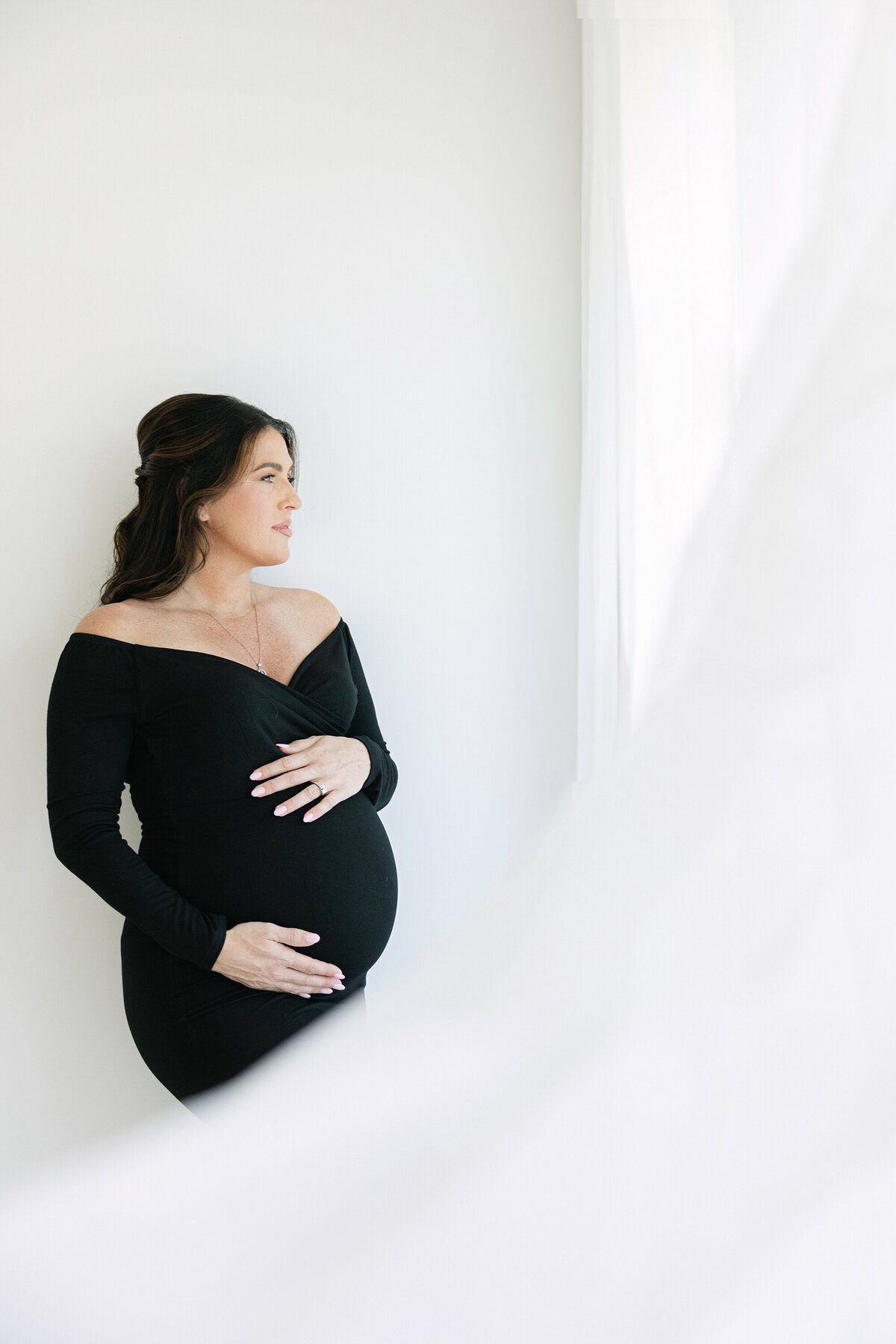pregnant mom in black dress with hands over belly