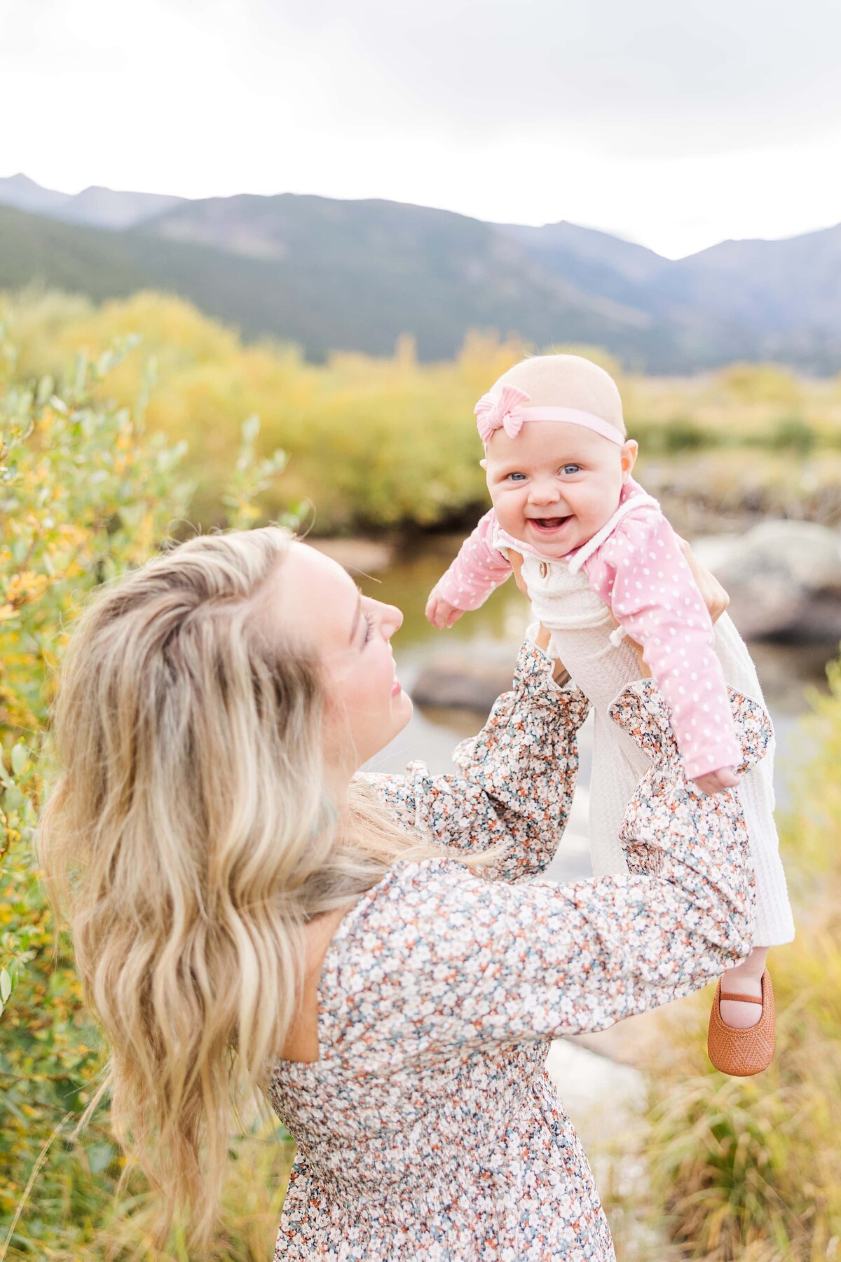 Mom is hold baby girl in the air while baby is laughing in Colorado