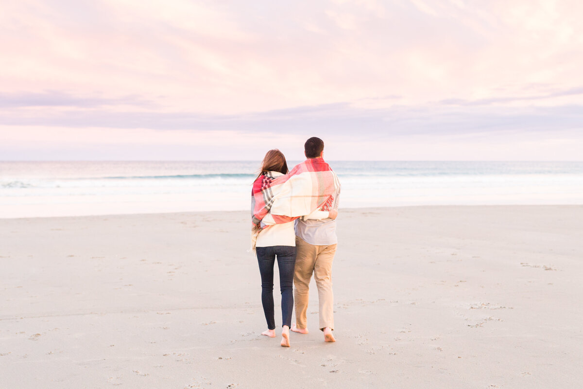 couple walking towards ocean during engagement session