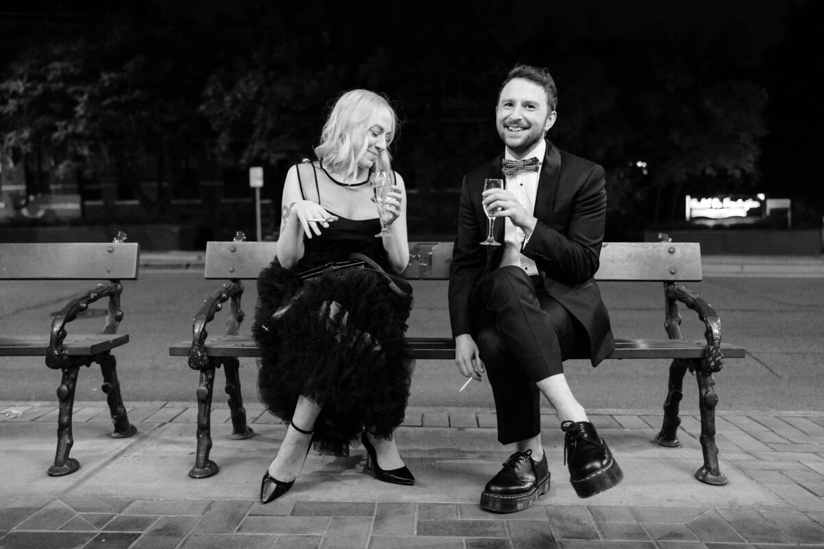 A couple of guests sitting on a bench outside the wedding reception.