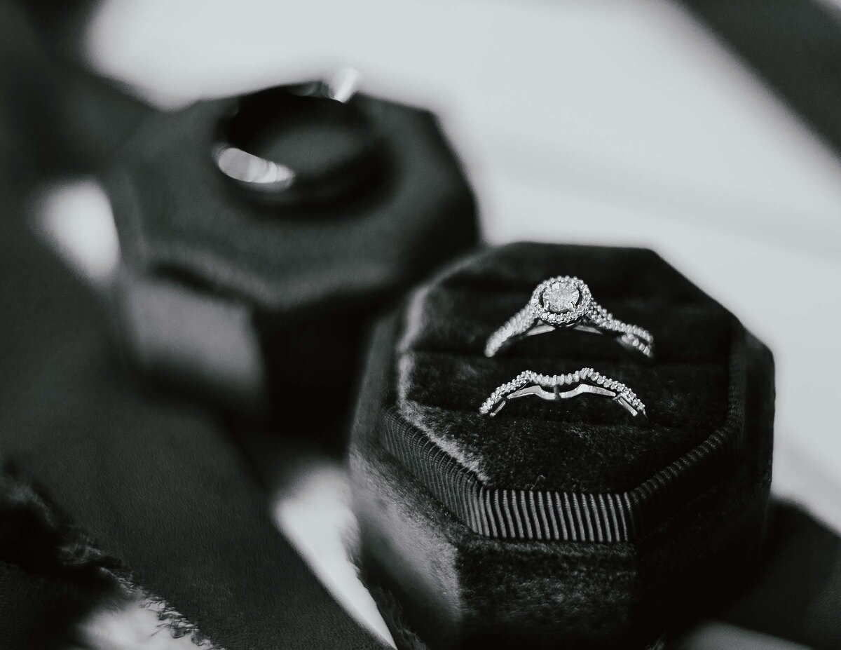 Maddie Rae Photography black and white detail shot of wedding rings. brides rings in ring box are focus and grooms ring in the background on the top of the ring box