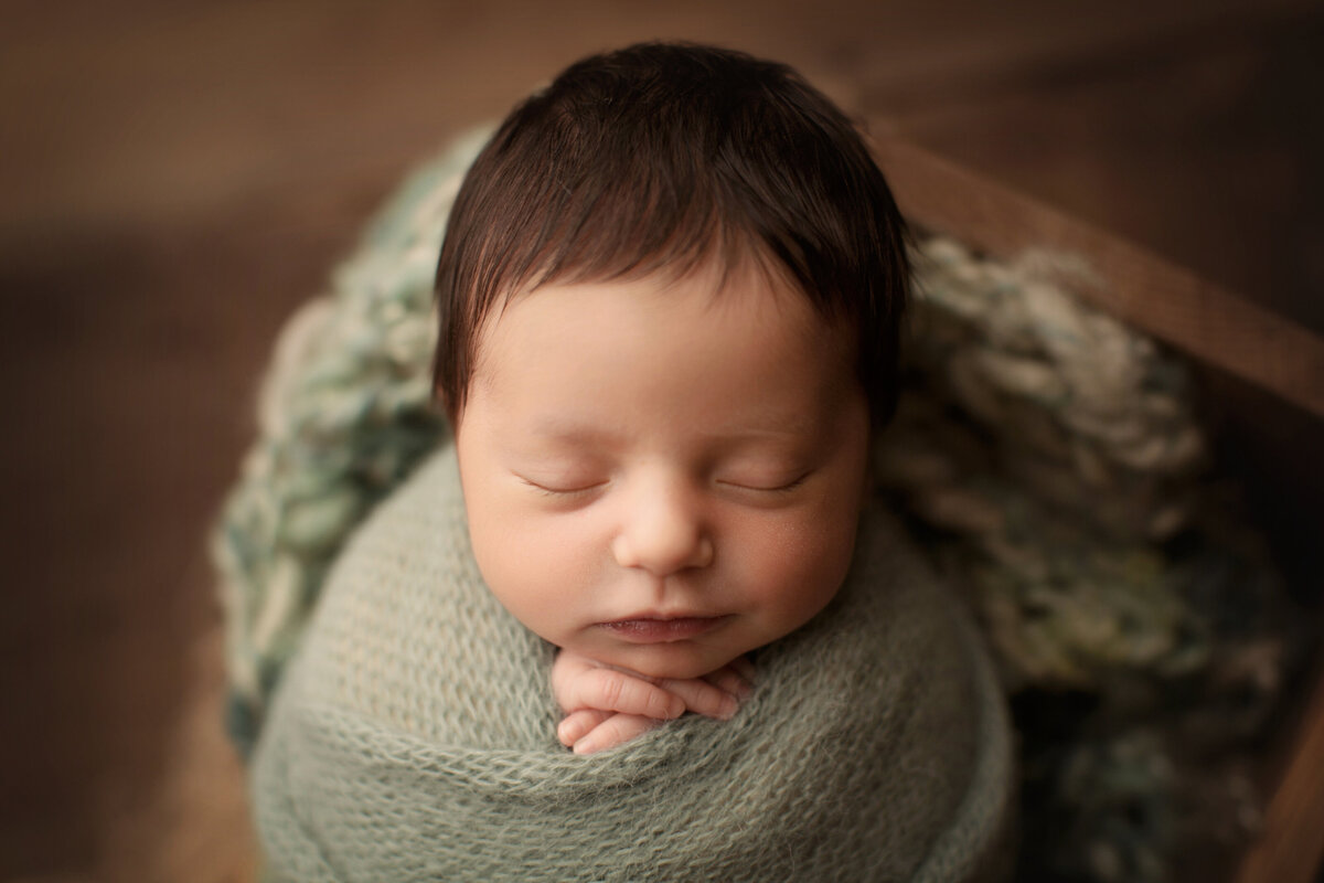baby girl in green blanket in cradle sleeping