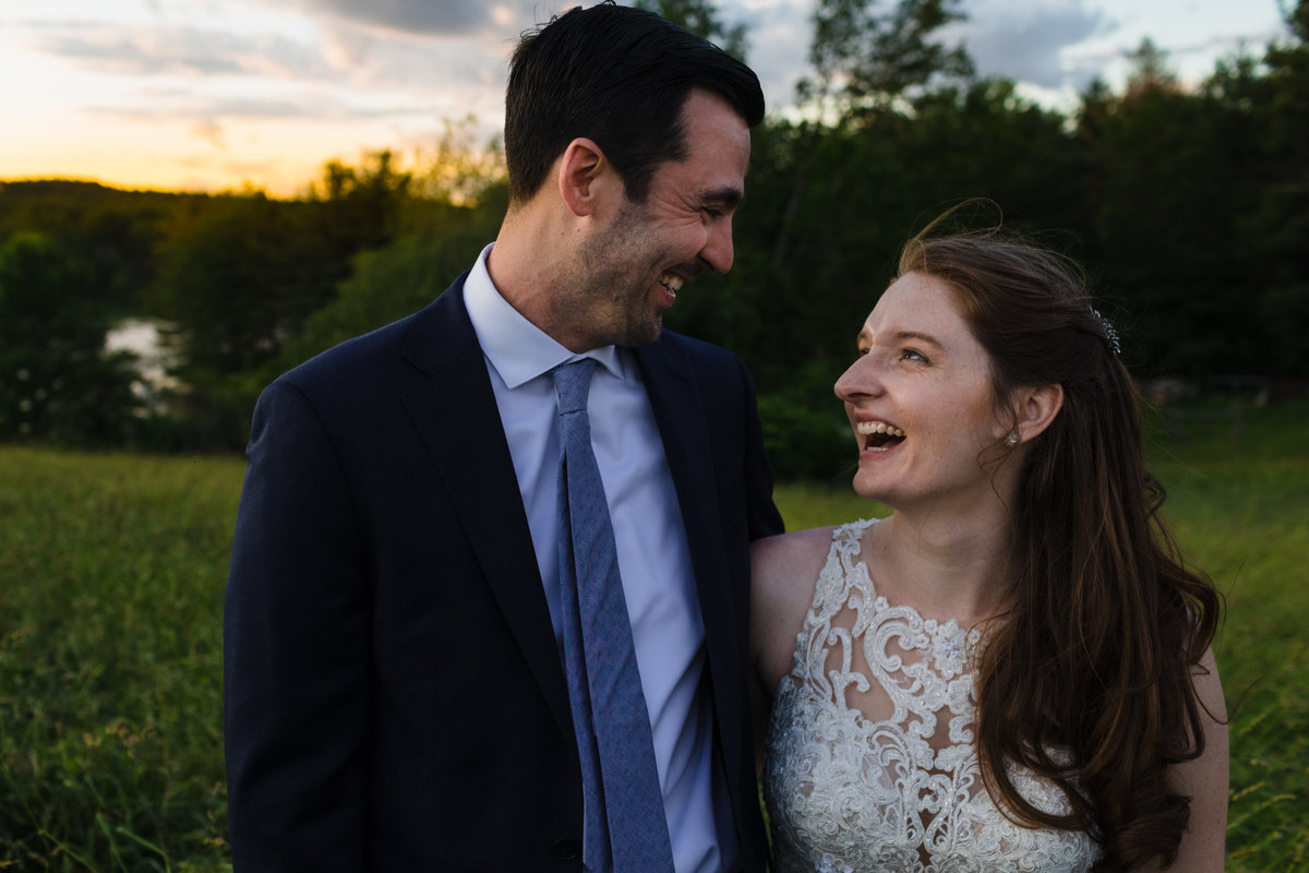 Kitz Farm Wedding couple laugh in the meadow as the sun sets behind them in Strafford NH