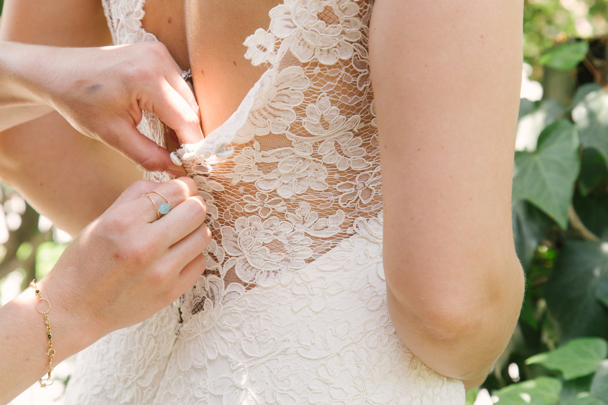 Bridesmaid helping bride button up wedding dress at Santa Barbara Courthouse wedding