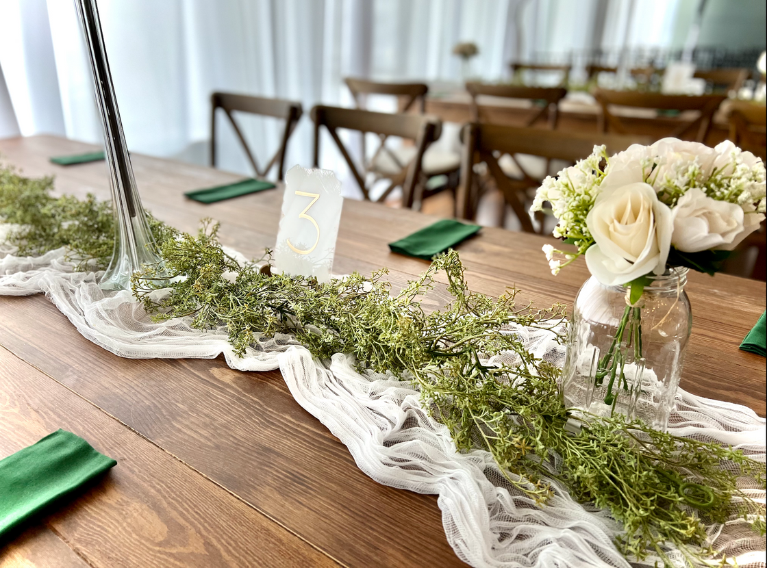 Rustic barn-style guest table at The District Clearwater event venue, adorned with a cheesecloth runner and charming rustic decor'.