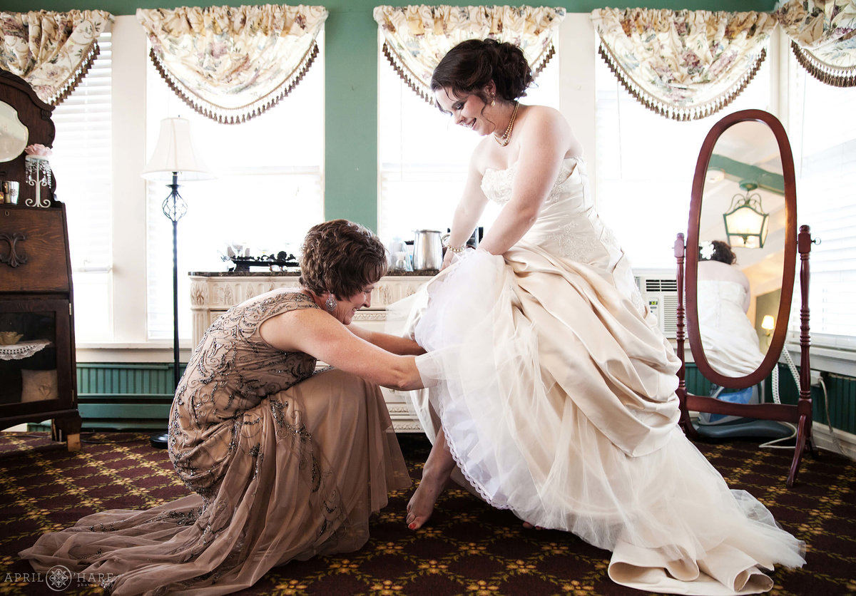 Mother of the bride helps with garter in the bridal suite at the Manor House in Littleton CO