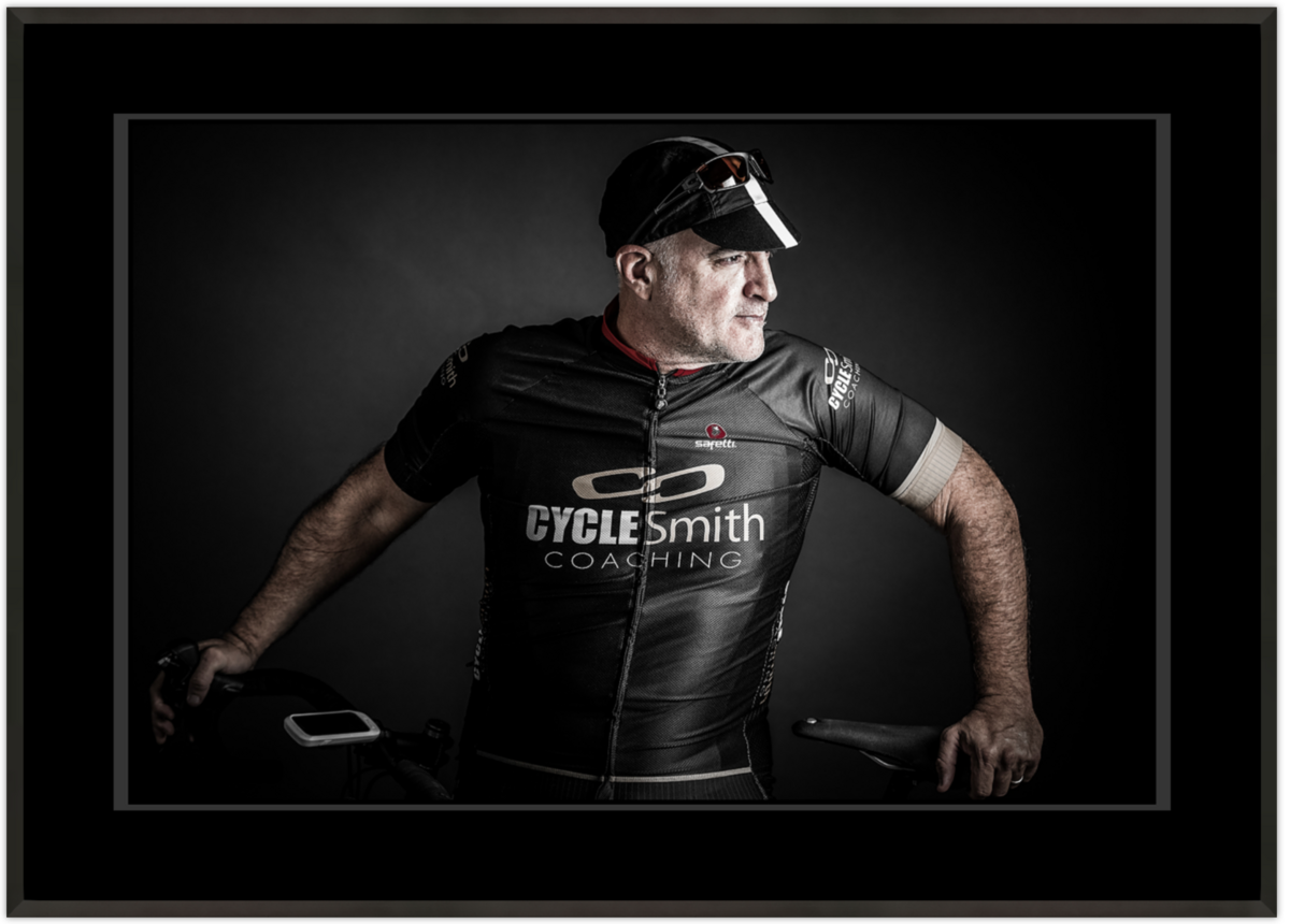 Derrick Birdsall in full Cycling Gear with Bike portrait mounted in a Black Flat Metal frame with Black Mat