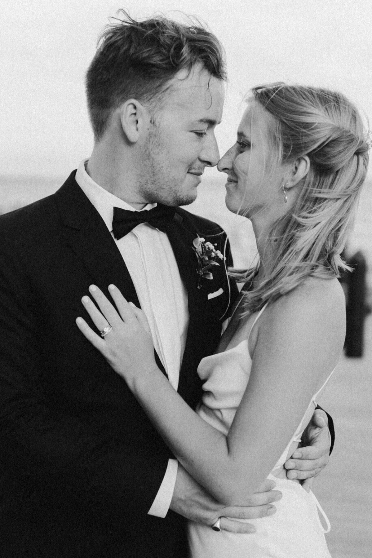 black and white image of bride and groom touches noses
