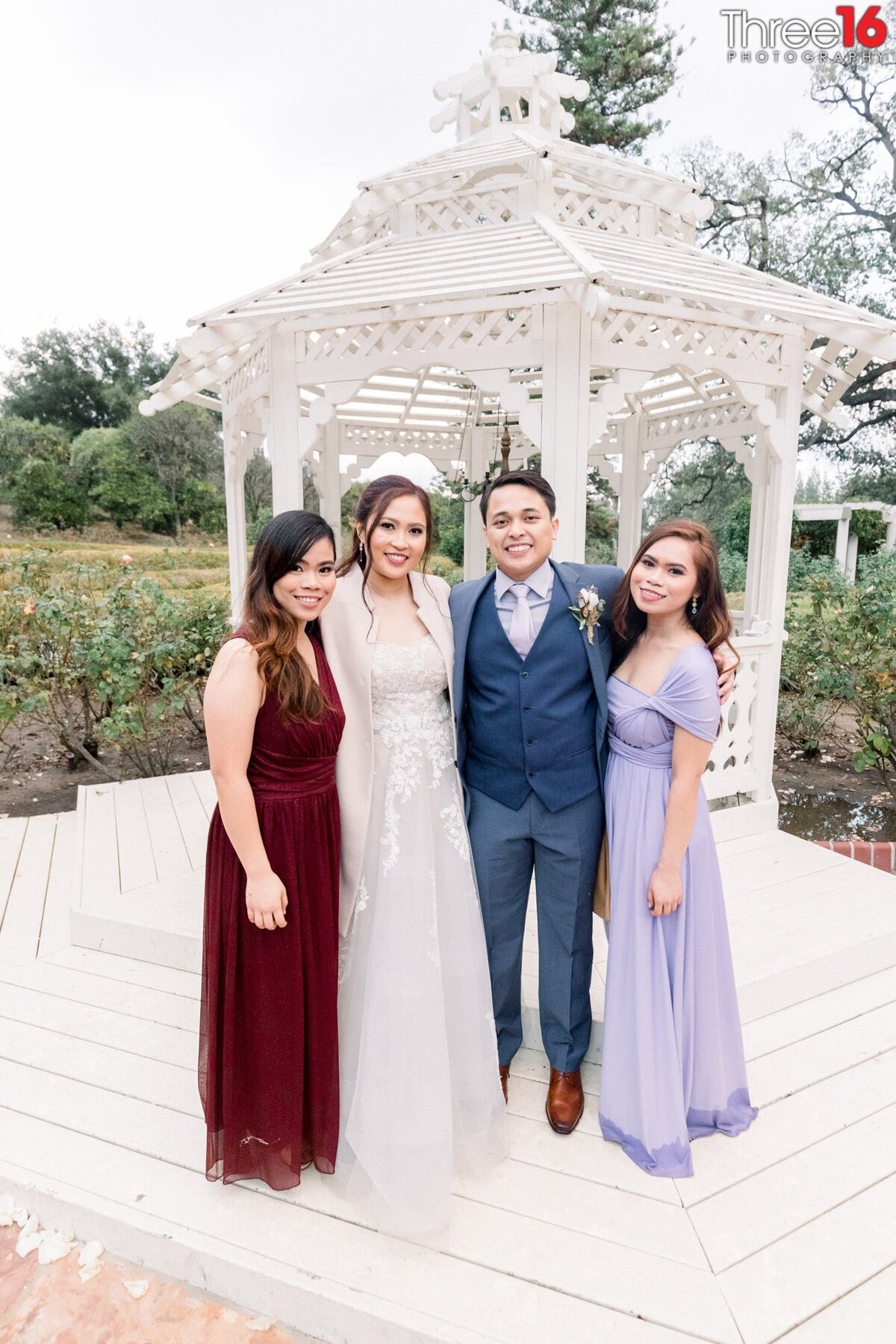 Bride and Groom pose for photos with Bridesmaids by the gazebo