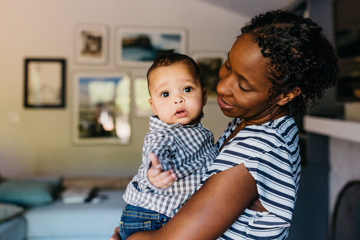 mother holding infant son in the living room during a family session in san francisco.