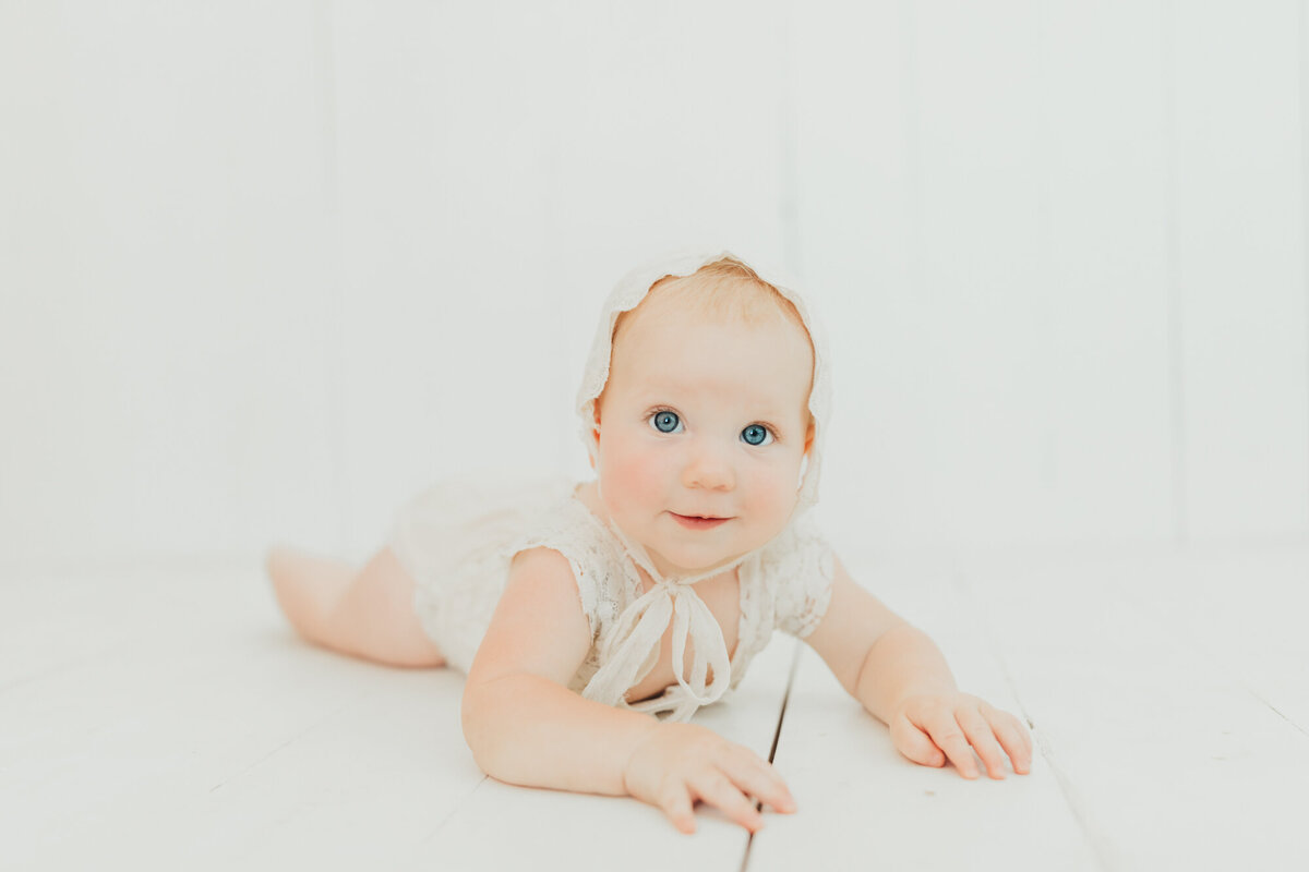 baby girl in bonnet in studio with Ally's Photography.