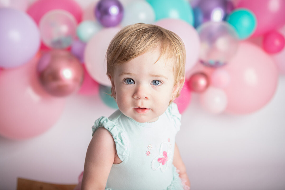 Birthday baby girl with a pink purple and teal balloon garland