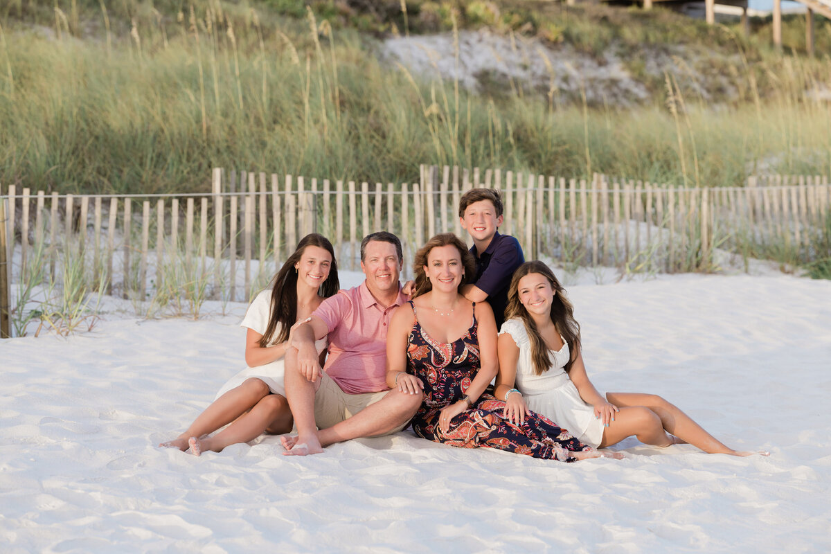 A family sitting on a white sand beach
