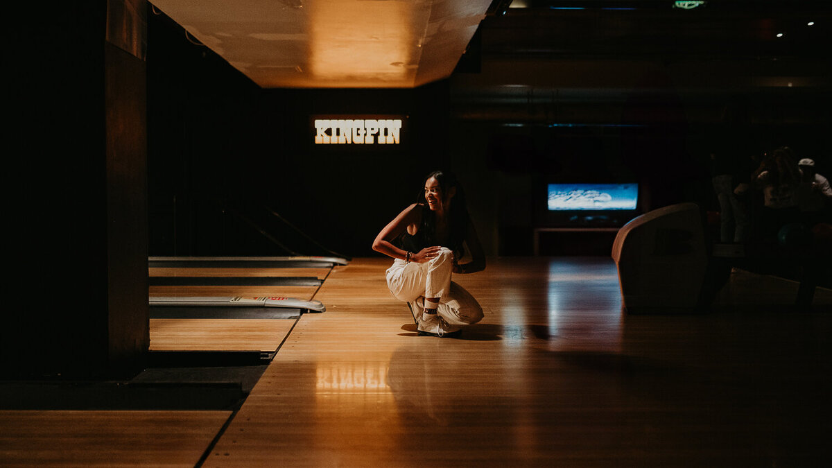 Girl crouching at the P&Co bowling event.