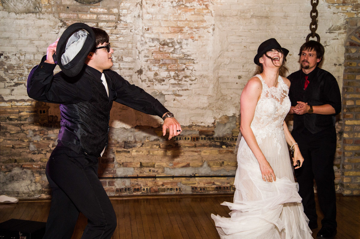 Bride and groom dance in hats.
